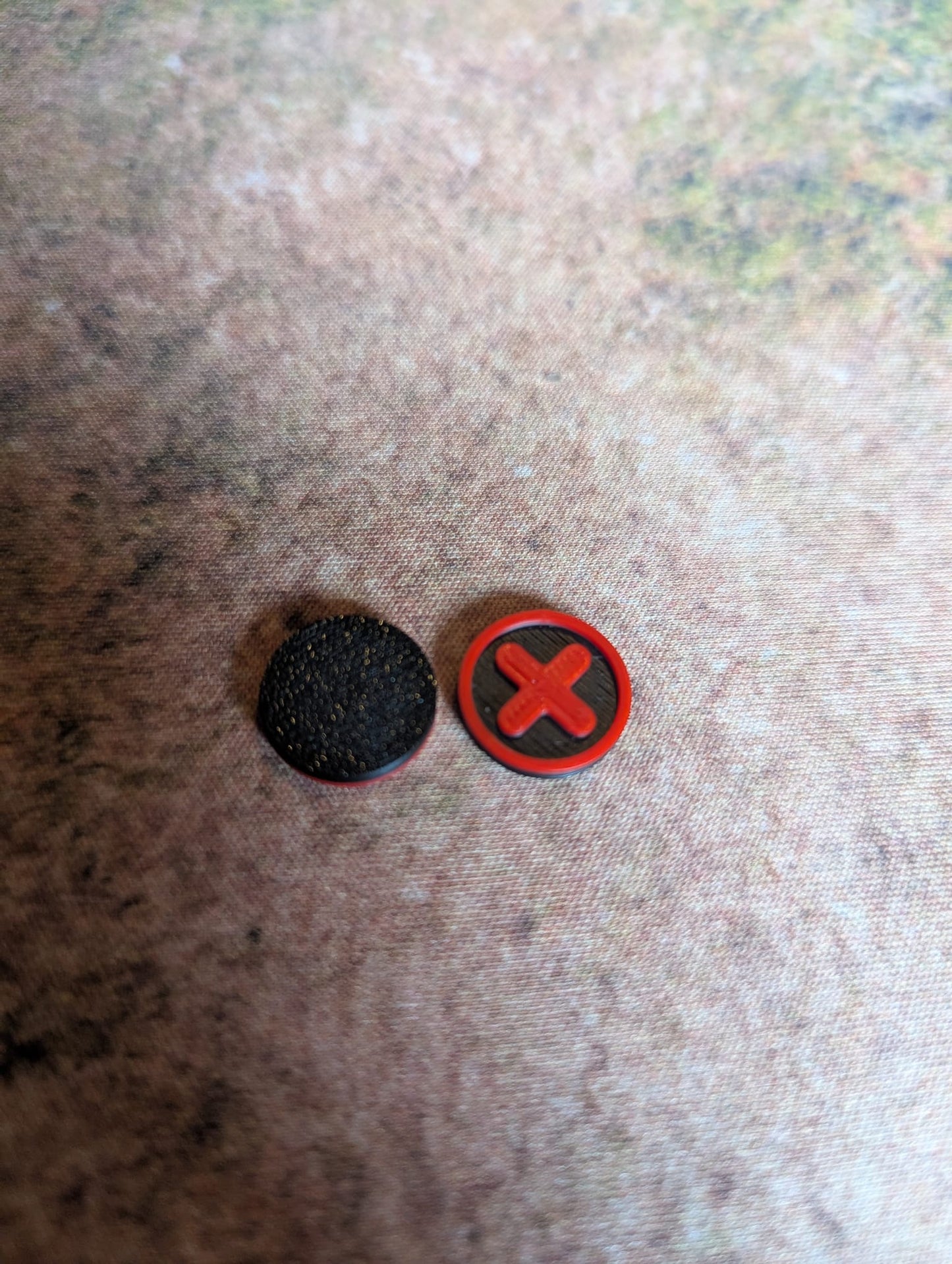 Two round stickers, one black and one with a red 'X', on a textured surface.